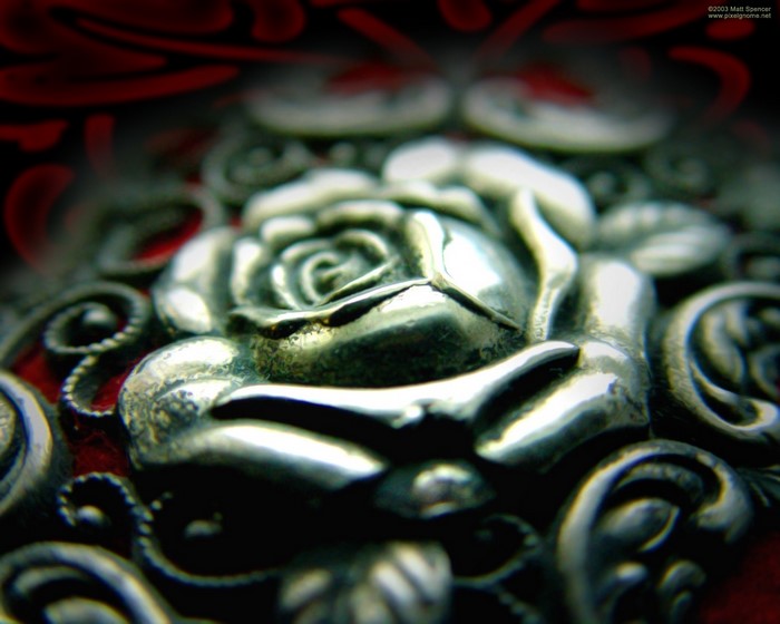 Close-up of a silver rose carving on a red background