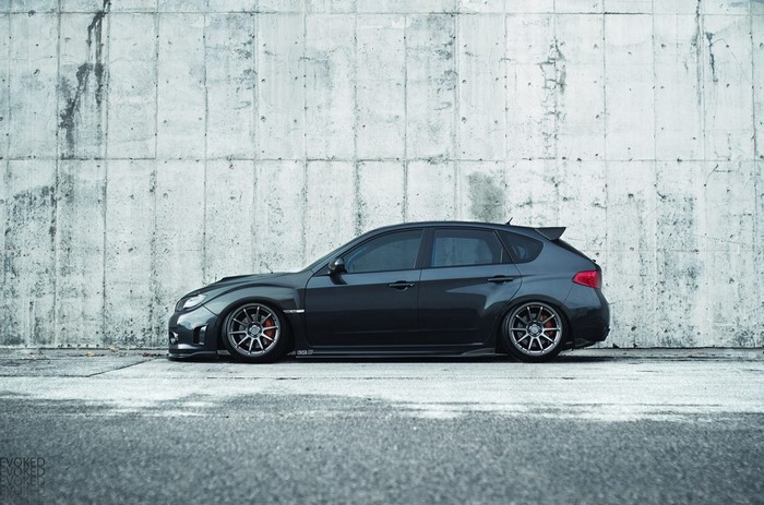 Dark grey Subaru Impreza WRX STI hatchback parked against concrete wall