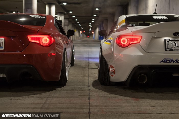 Two sports cars, a red Toyota 86 and a white Subaru BRZ, parked in a tunnel.