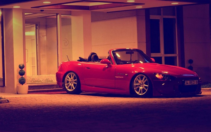 Red Honda S2000 convertible parked outside building