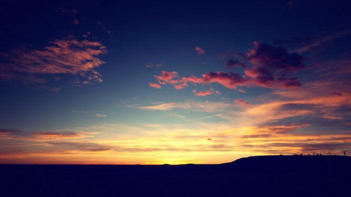 Sunset over a dark landscape with clouds