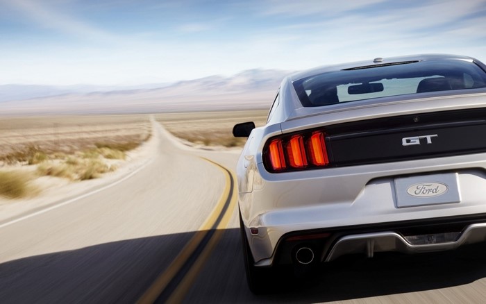 Silver Ford Mustang GT driving on a desert road