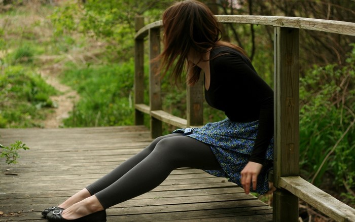 Woman sitting on a wooden bridge in a forest