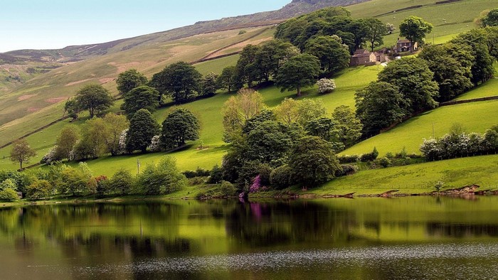 Green hills with trees reflected in a lake