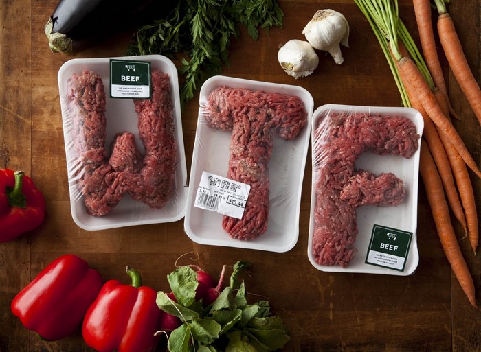 Ground beef arranged in letters on trays with produce
