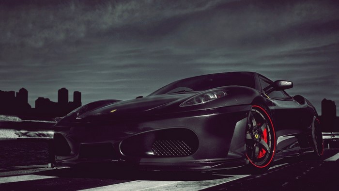 Black Ferrari F430 parked with city skyline in background