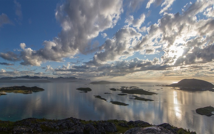 Islands and Mountains Reflected in Calm Water Under Cloudy Sky