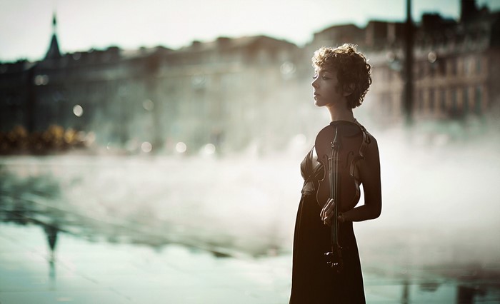 Woman holding a violin in front of a city