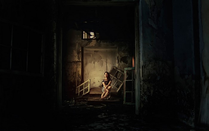Woman sitting in a dark, abandoned room