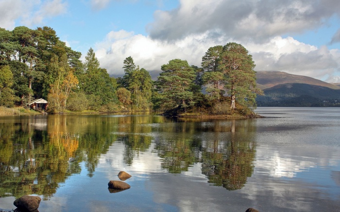 Trees reflected in a lake with mountains in the background