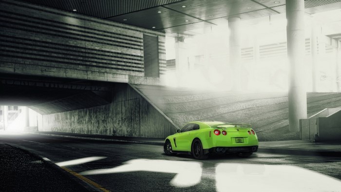 Green Nissan GT-R driving under a concrete structure