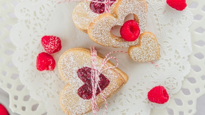 Heart-shaped raspberry jam cookies dusted with powdered sugar