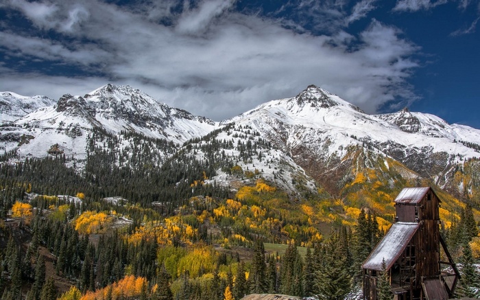 Snow-capped mountains with autumn trees and old mine building