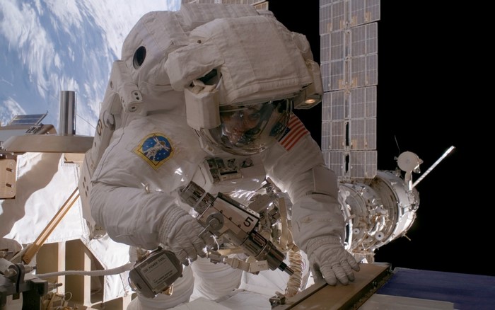 Astronaut performing spacewalk with tools