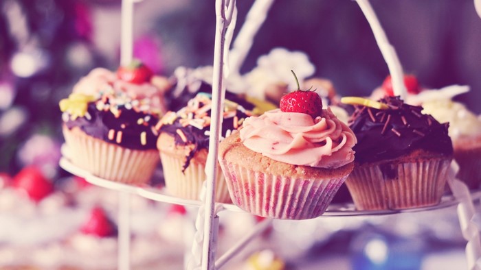 Cupcakes with frosting and strawberries on a tiered stand