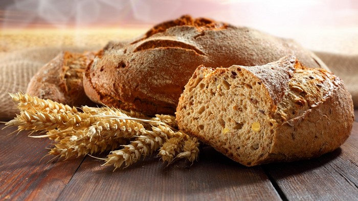 Loaves of bread with wheat stalks on a wooden table