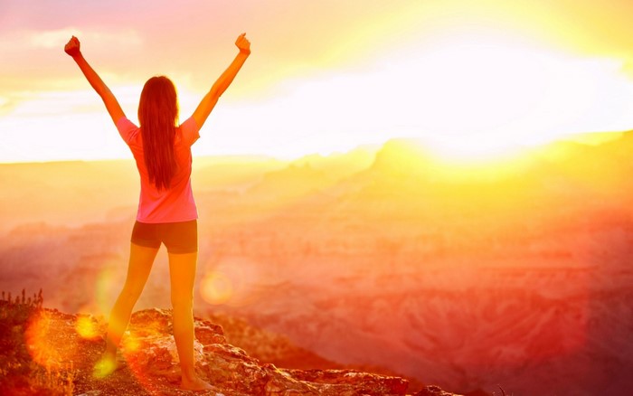Woman with arms raised at sunset