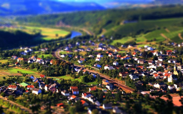 Aerial view of a village nestled in a valley with a river and hills