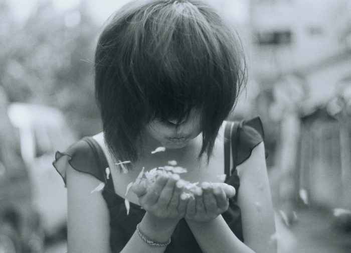 Girl blowing flower petals in monochrome