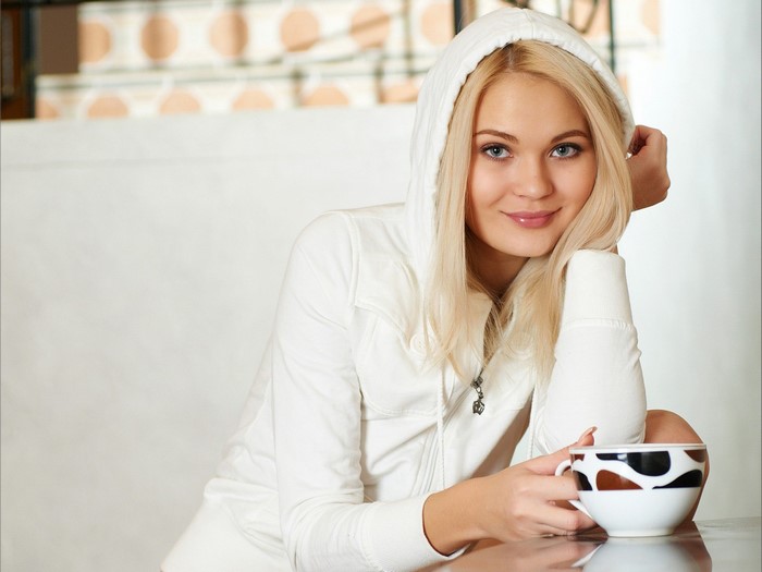 Blonde Woman in White Hoodie Smiling Holding Cup
