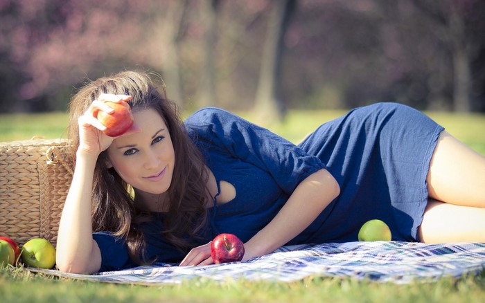 Woman in blue dress with apples on picnic blanket
