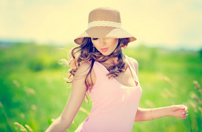 Woman in a pink dress and hat in a field