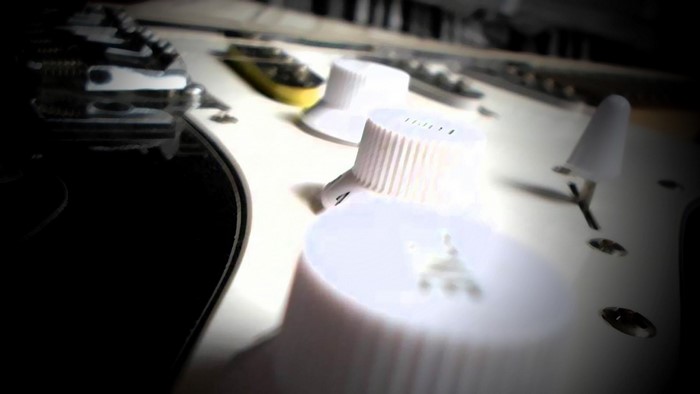 Close-up of white electric guitar knobs and bridge