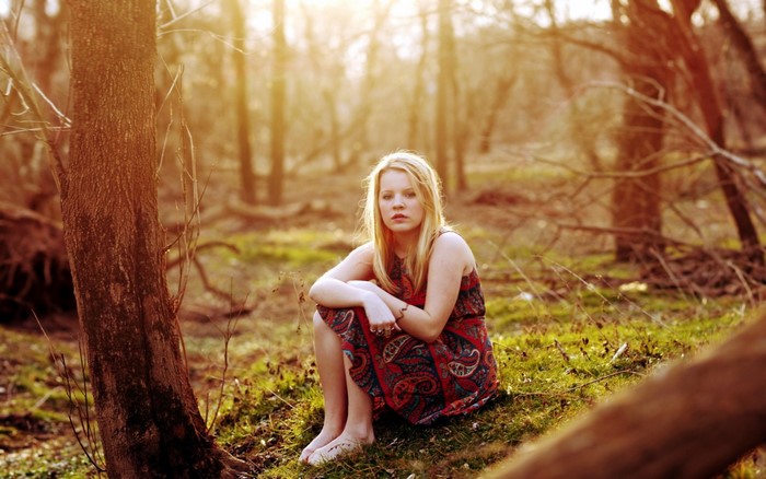 Young woman sitting in a sunlit forest