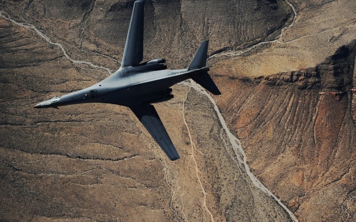 Rockwell B-1 Lancer bomber flying over desert canyon