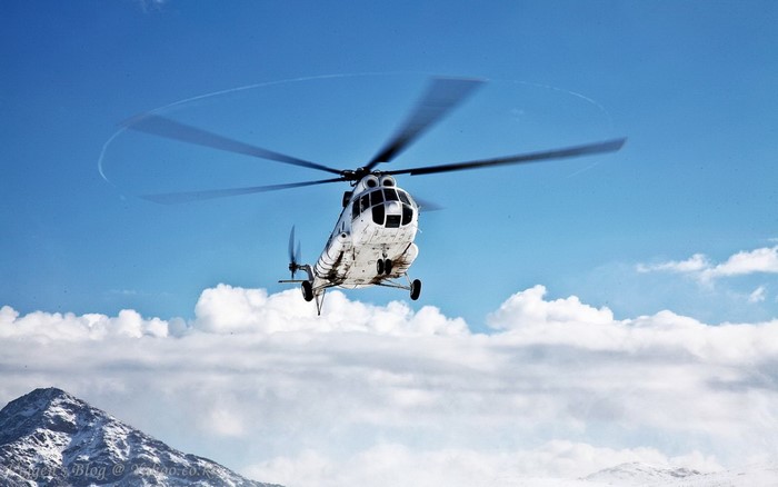 White Mil Mi-17 helicopter flying over mountains