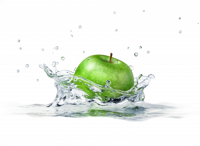Green apple splashing into water with droplets