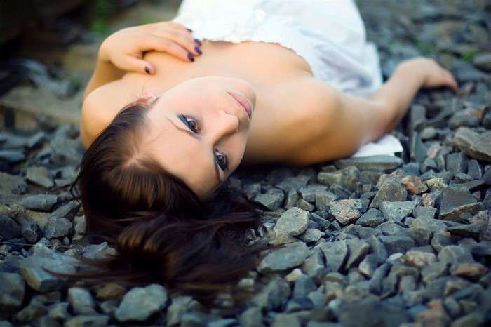 Woman lying on rocks wearing a white dress