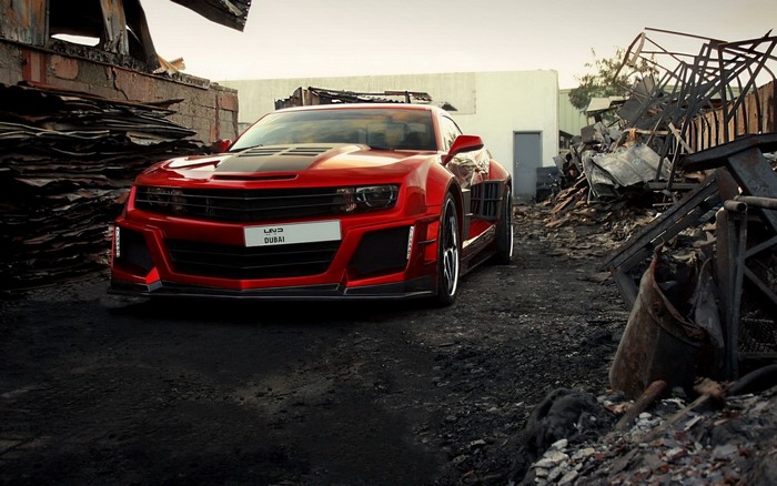 Red Chevrolet Camaro in a junkyard