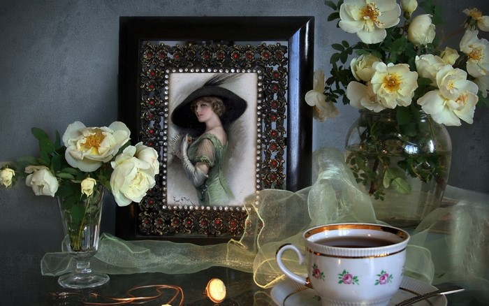 Still life with painting of a woman, roses, and tea cup