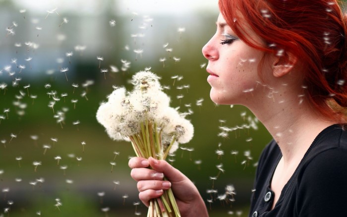 Woman blowing dandelion seeds