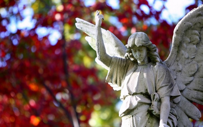 Stone angel statue with autumn leaves