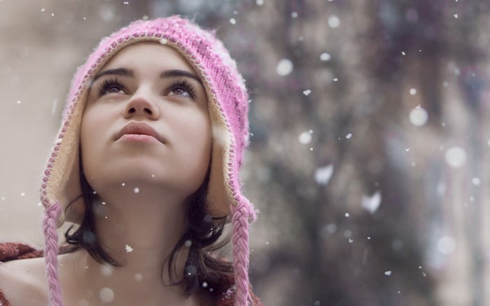 Young woman in pink hat looking up at snow
