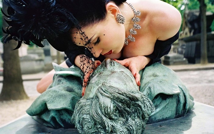Woman in black outfit and veil with statue