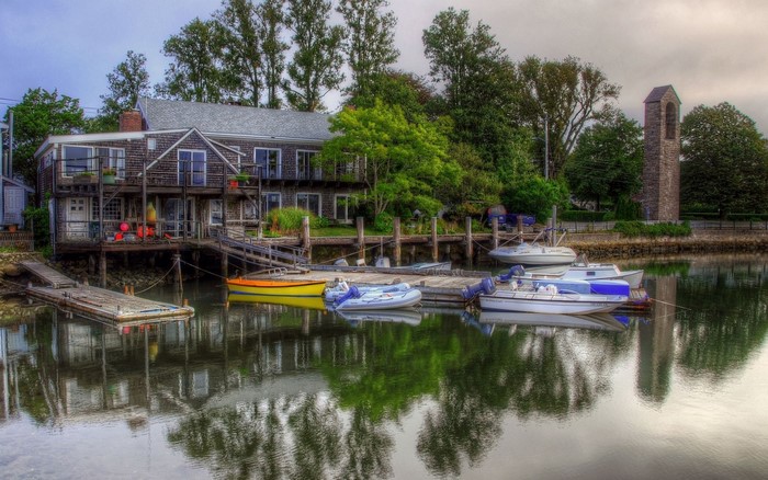 Boats docked by a wooden building with a stone tower in the background