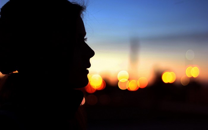 Silhouette of a woman at sunset with bokeh lights