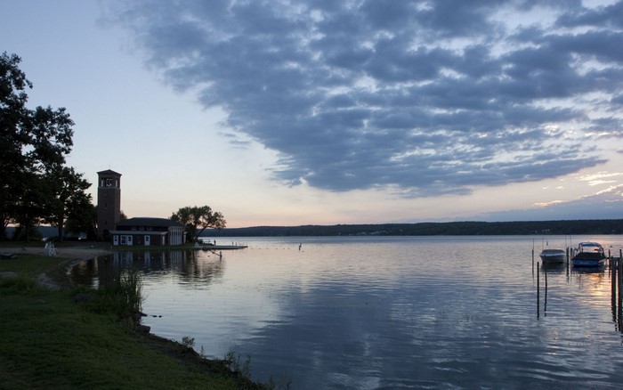 Sunset over a calm lake with a tower and boats