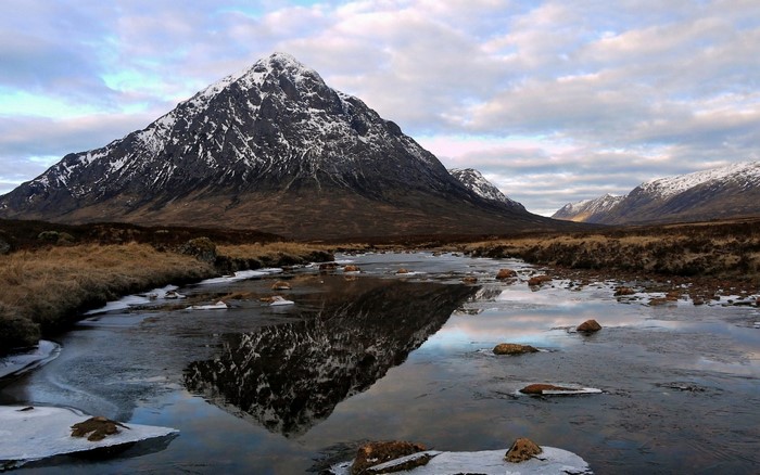 Snow-capped mountain reflected in a frozen stream in Scotland