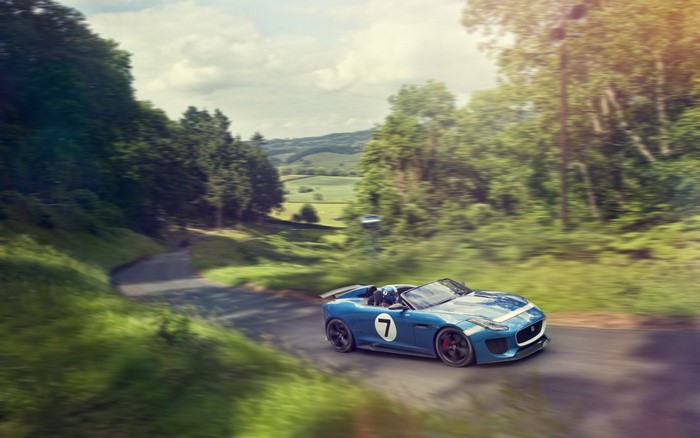 Blue Jaguar F-Type sports car driving on a winding road