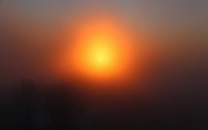 Sun setting through fog with lens flare