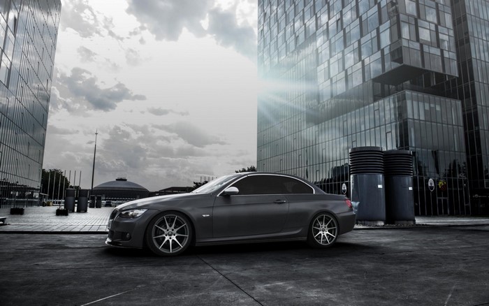 Gray BMW sports car parked in front of modern glass buildings