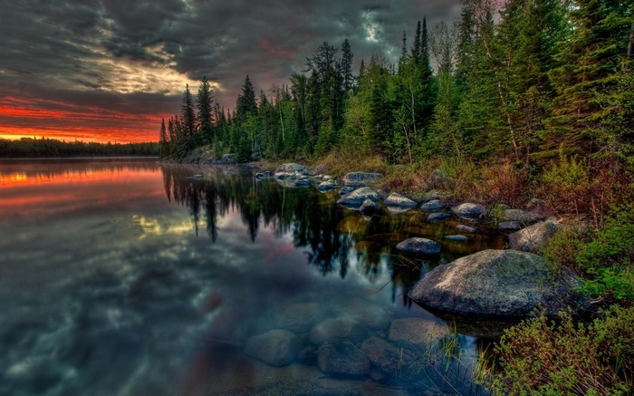 Sunset over a lake with a forest and rocks
