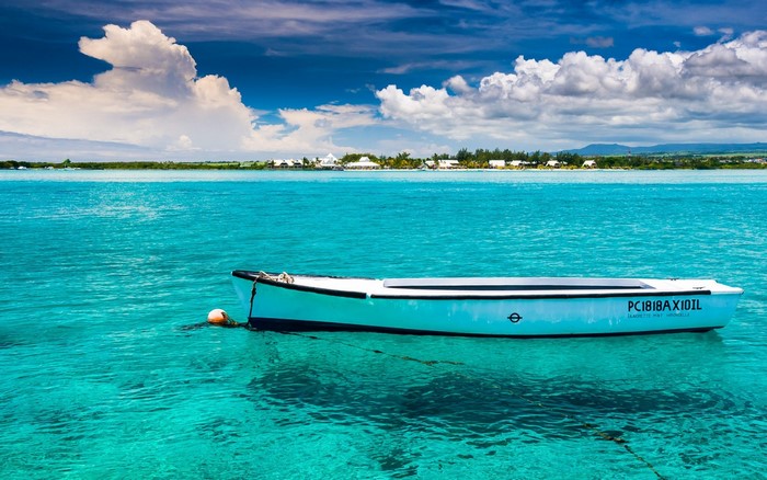 White boat floating in turquoise water near an island