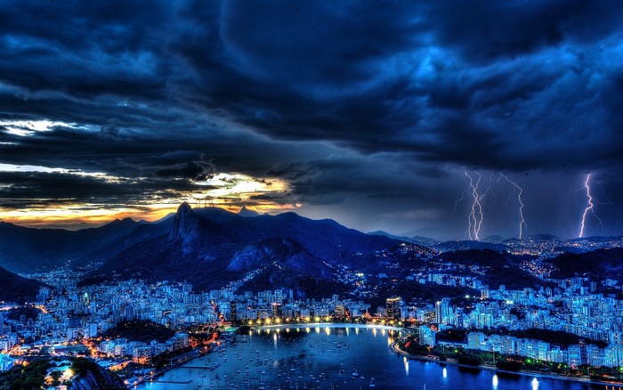 Cityscape with mountains and lightning storm at dusk