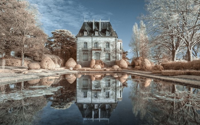 Chateau reflected in a pond with bare trees