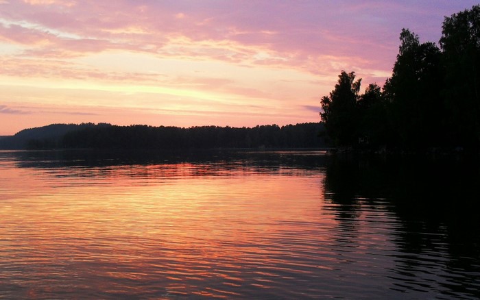 Sunset over a calm lake with silhouetted trees